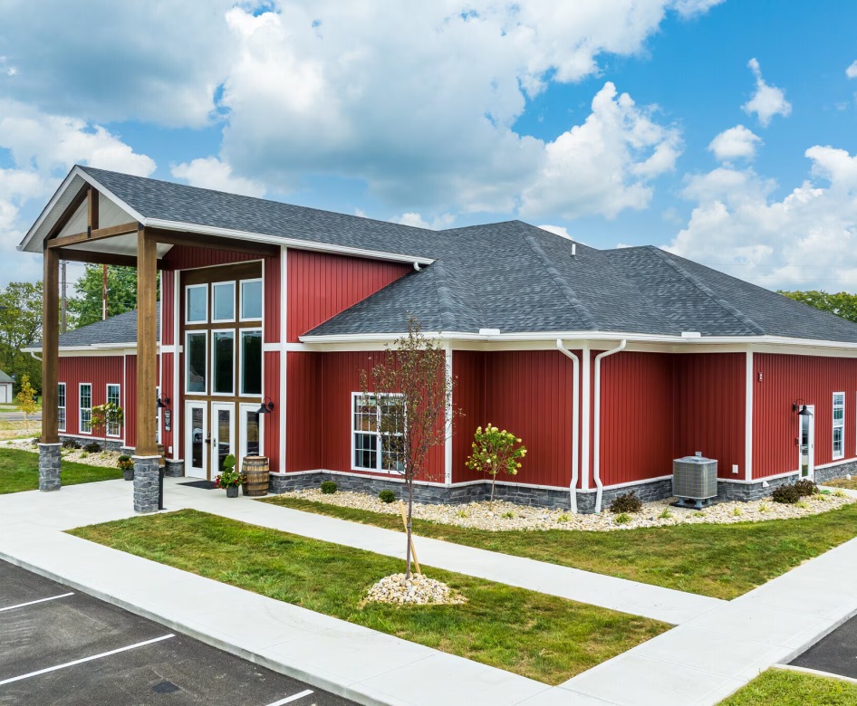 a red building with grass and a small tree in front of it