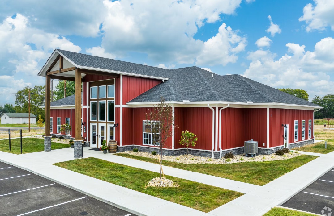 a red building with grass and a small tree in front of it