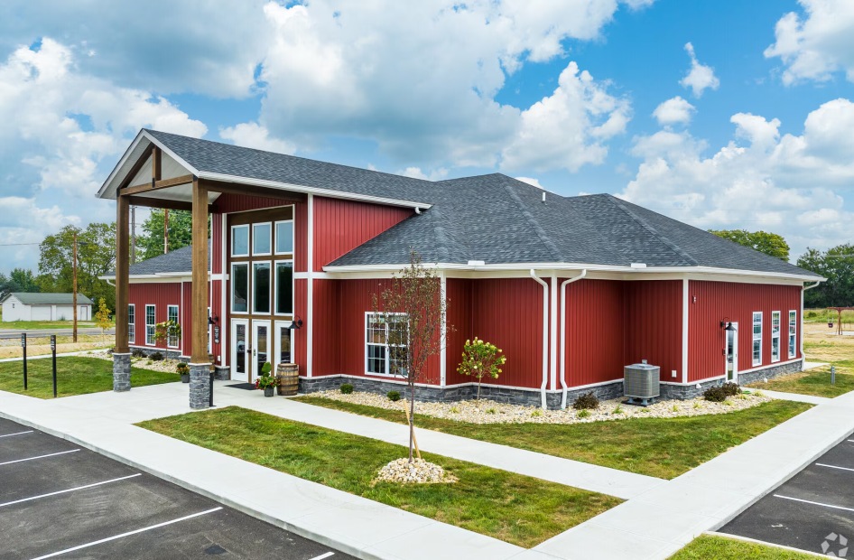 a red building with grass and a small tree in front of it