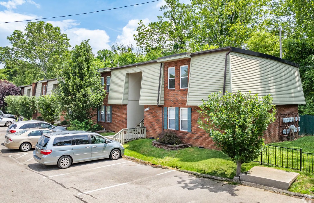 a building with trees and a parking lot in front of it